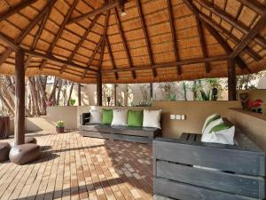 a patio with two benches under a wooden umbrella at Timeless Lodge in Umkomaas