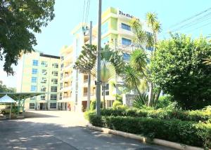 a building with palm trees in front of a street at โรงแรม ชาโตว์วิสต้า in Chon Buri