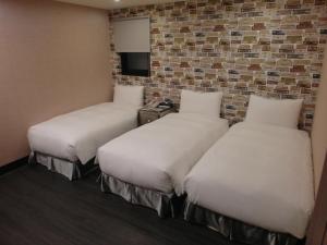 duas camas num quarto com uma parede de tijolos em Hotel Fun - Linsen em Taipei