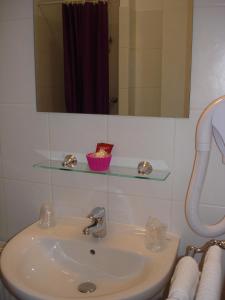 a bathroom sink with a mirror and a shelf above it at Hotel Du Cheval Blanc in Saint-Pol-de-Léon