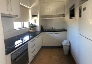 una pequeña cocina con armarios blancos y fregadero en Apt 56 Riverview Holiday Apartments en Kalbarri