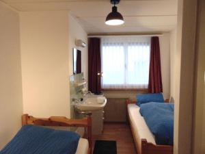 1 dormitorio con 2 camas, lavabo y ventana en Ferienwohnung Casa Plauns-iu, en Sedrun