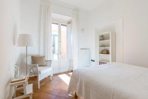 a white bedroom with a bed and a chair at Casa 45 in Salerno