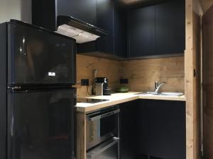 cocina con armarios negros y nevera negra en Appartement 3 étoiles - au pied des pistes, en Valmeinier