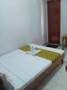 1 dormitorio con 1 cama con sábanas blancas y mantas amarillas en Bohol Coop Tourist Inn, en Tagbilaran City