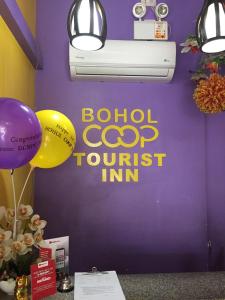 una habitación con una pared púrpura con un cartel y globos en Bohol Coop Tourist Inn, en Tagbilaran City