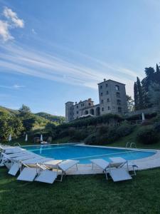 une piscine avec des chaises et un bâtiment en arrière-plan dans l'établissement Badia San Nicolò di Campolongo - Appartamento D'Onofrio, à Valfabbrica