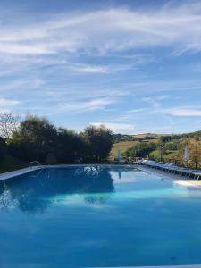 une grande piscine bleue avec un ciel bleu dans l'établissement Badia San Nicolò di Campolongo - Appartamento D'Onofrio, à Valfabbrica