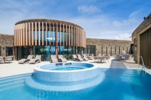 uma piscina com cadeiras e um edifício em The Headland Hotel and Spa em Newquay