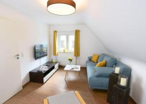 ein Wohnzimmer mit einem blauen Sofa und einem TV in der Unterkunft Ferienwohnungen Schwarzwaldhäusle in Freudenstadt