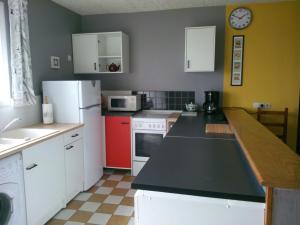 GraignesにあるEntre Ciel et Maraisのキッチン(黒いカウンタートップ、白い冷蔵庫付)