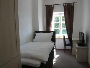 ein Schlafzimmer mit einem Bett, einem Fenster und einem Stuhl in der Unterkunft Pension Lechner in Vilsbiburg