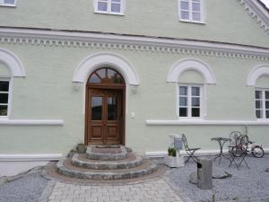 ein weißes Haus mit einer Holztür und einer Terrasse in der Unterkunft Pension Lechner in Vilsbiburg