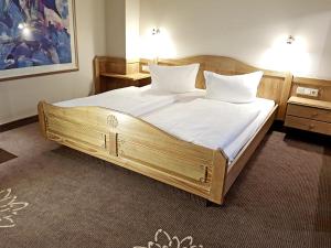 Schlafzimmer mit einem Holzbett mit weißer Bettwäsche und Kissen in der Unterkunft Hotel in den Herrnwiesen in Wertheim