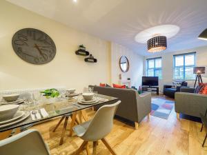 a living room with a table and a clock on the wall at 2 Brocklehurst Cottages in Buxton