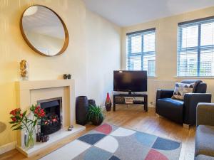 a living room with a fireplace and a mirror at 2 Brocklehurst Cottages in Buxton