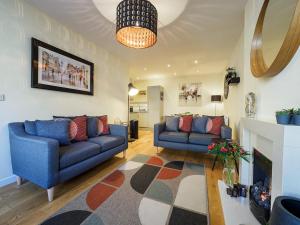 a living room with two blue couches and a fireplace at 2 Brocklehurst Cottages in Buxton