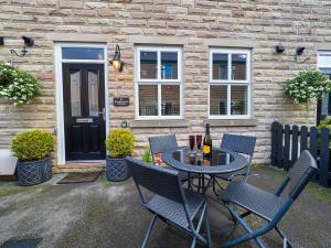 a patio with chairs and a table with a bottle of wine at 2 Brocklehurst Cottages in Buxton