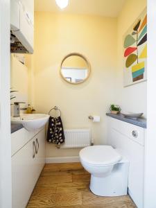 a bathroom with a toilet and a sink and a mirror at 2 Brocklehurst Cottages in Buxton