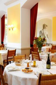 ニヨンにあるHôtel Colombetの白いテーブルと椅子と像のあるレストラン
