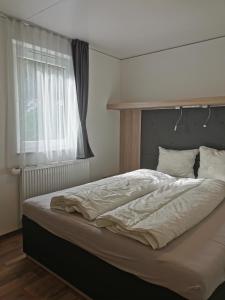 1 cama grande en un dormitorio con ventana en Seecamping Berghof - Mobilheime, en Landskron