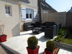 eine Terrasse mit schwarzen Möbeln und Pflanzen im Hinterhof in der Unterkunft Gîte de Eric et Rose in Bernières-sur-Mer