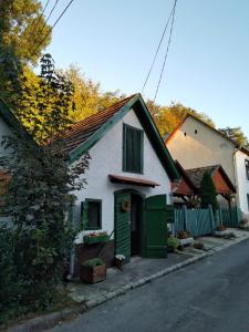 una pequeña casa blanca con una puerta verde en una calle en Zebegényi Présház, en Zebegény