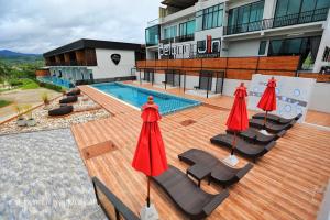 a deck with chairs and umbrellas next to a swimming pool at Belong Jin The Dam Resort in Ban Pha Saeng Lang