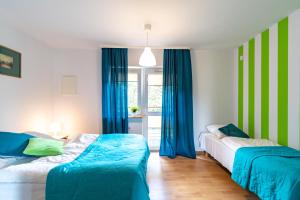 two beds in a room with blue curtains at Apartamenty Jeanette in Rowy