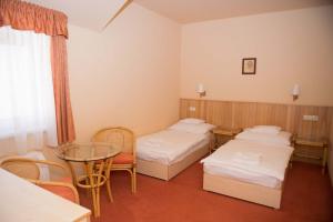 Cette chambre comprend deux lits, une table et des chaises. dans l'établissement Termálhotel Martfű, à Martfů