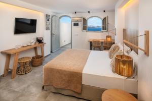 a hotel room with a bed and a table and a television at Kokkinos Villas in Akrotiri