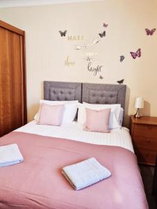 a bedroom with a large bed with pink sheets and butterflies on the wall at Royal Victoria House in Dundee