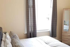 a bedroom with a bed and a window with curtains at Contemporary Apartment in Leicester