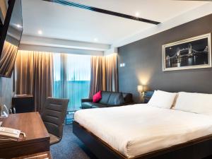 a bedroom with a large bed and a large window at Crowne Plaza London - Kingston, an IHG Hotel in Kingston upon Thames