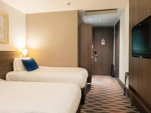 a hotel room with a bed and a television at Crowne Plaza London - Kingston, an IHG Hotel in Kingston upon Thames