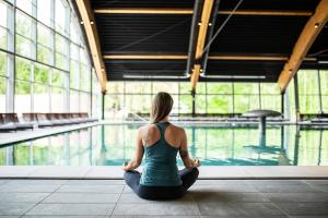 Eine Frau, die in einer Yoga-Pose vor einem Pool sitzt. in der Unterkunft Hotel Terme Sveti Martin in Sveti Martin na Muri
