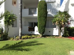 una casa blanca con árboles y un patio en Apartment Costalita, direct beach access, ground floor, salt water pool, en Estepona