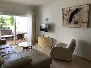 sala de estar con sofá y TV en Apartment Costalita, direct beach access, ground floor, salt water pool, en Estepona