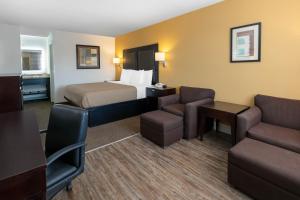 a hotel room with a bed and a couch and chairs at Days Inn by Wyndham Granbury in Granbury