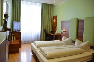 a hotel room with two beds and a desk at Arthotel Munich in Munich