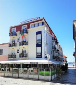 een groot wit gebouw aan de straatkant bij Hotel Atlântica in São Martinho do Porto