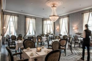 uma sala de jantar com mesas e cadeiras e um lustre em Hotel Victoria em Stavanger