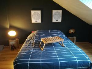Un dormitorio con una cama azul con un banco. en Le Petit Loft Vosgien, en Cornimont