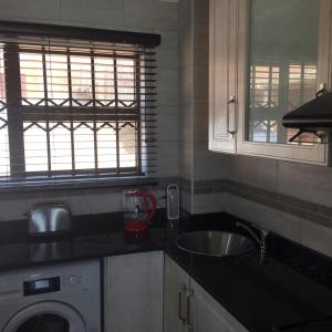 a kitchen with a sink and a washing machine at Villa Siesta Flat No 1 in Margate
