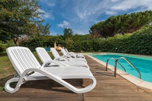 a row of white chairs sitting next to a swimming pool at Casa Vacanze Airone in Muravera