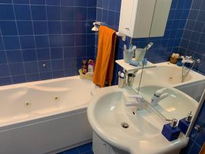 a blue tiled bathroom with a sink and a tub at Appartamento Pila in Pila