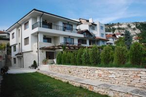 a large white house with a stone wall at Guest House Balchik Hills in Balchik