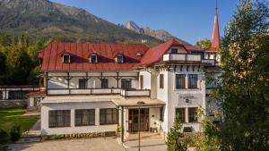 a large white building with a red roof at Villa Dr Szontagh Est. 1876 in Vysoke Tatry - Novy Smokovec