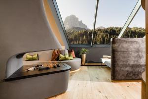 a living room with a fireplace and a large window at Hotel Touring Dolomites in Santa Cristina in Val Gardena