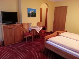 Schlafzimmer mit einem Bett, einem TV und einem Tisch in der Unterkunft Gasthof Zur Post in Bad Goisern